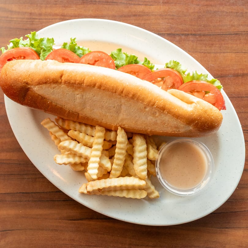 A Newyork Pizza Macedonia sub sandwich with lettuce and tomatoes, crinkle-cut fries, and dipping sauce.